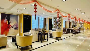 A hotel lobby with seating areas, a reception desk, and a bookshelf.