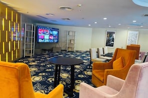 A hotel lobby with a large flat-screen TV, comfortable seating, and a patterned carpet. - Eaself Hotel (Beijing)