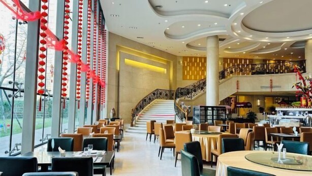 A modern restaurant with a central staircase, multiple dining areas, and large windows. - Eaself Hotel (Beijing)