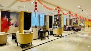 A spacious lobby with a modern design, featuring a long reception desk, comfortable seating areas, and a large bookshelf. - Eaself Hotel (Beijing)