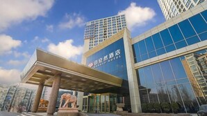 A modern hotel entrance with a glass facade, a covered entrance area, and a statue of an elephant. - Eaself Hotel (Beijing)
