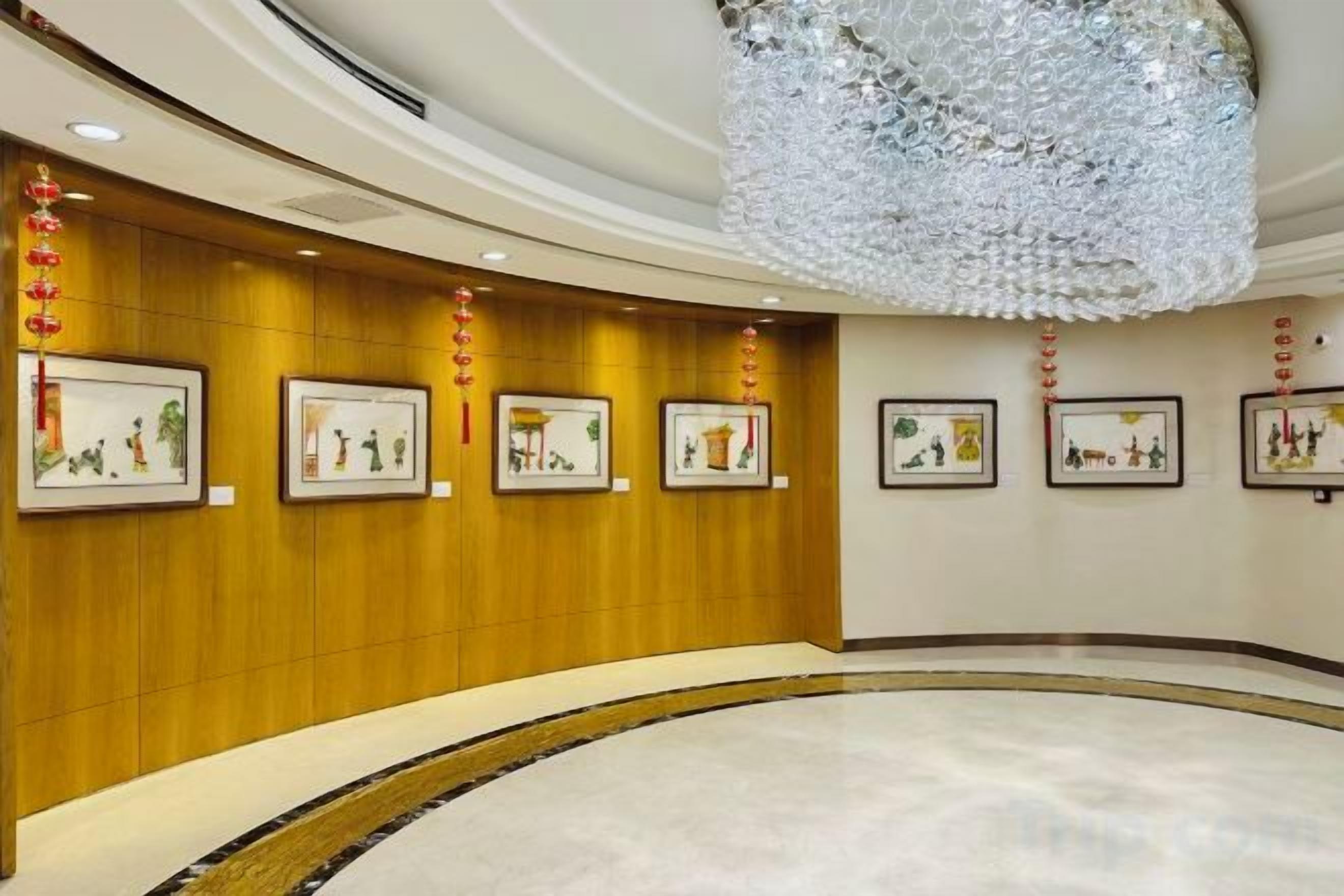 A lobby with a curved marble floor, wooden panel walls, and framed artwork.