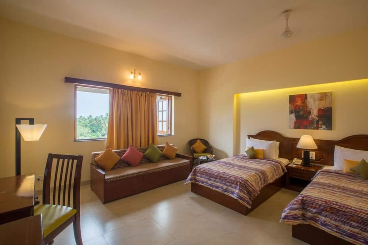 A hotel room with two beds, a sofa, a dining table, and a chair.