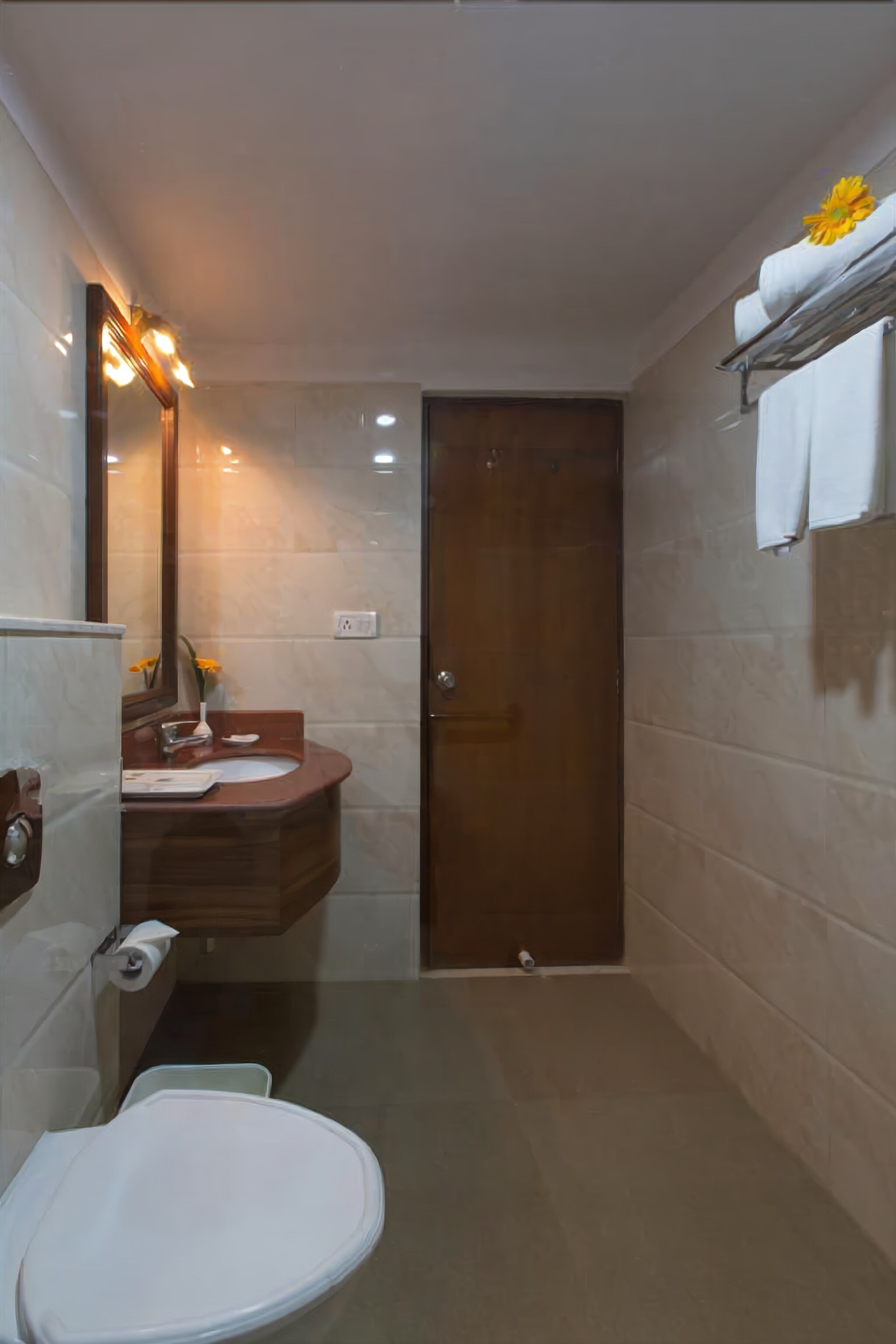 Une salle de bain comprenant des toilettes, un lavabo, un miroir et un espace douche.