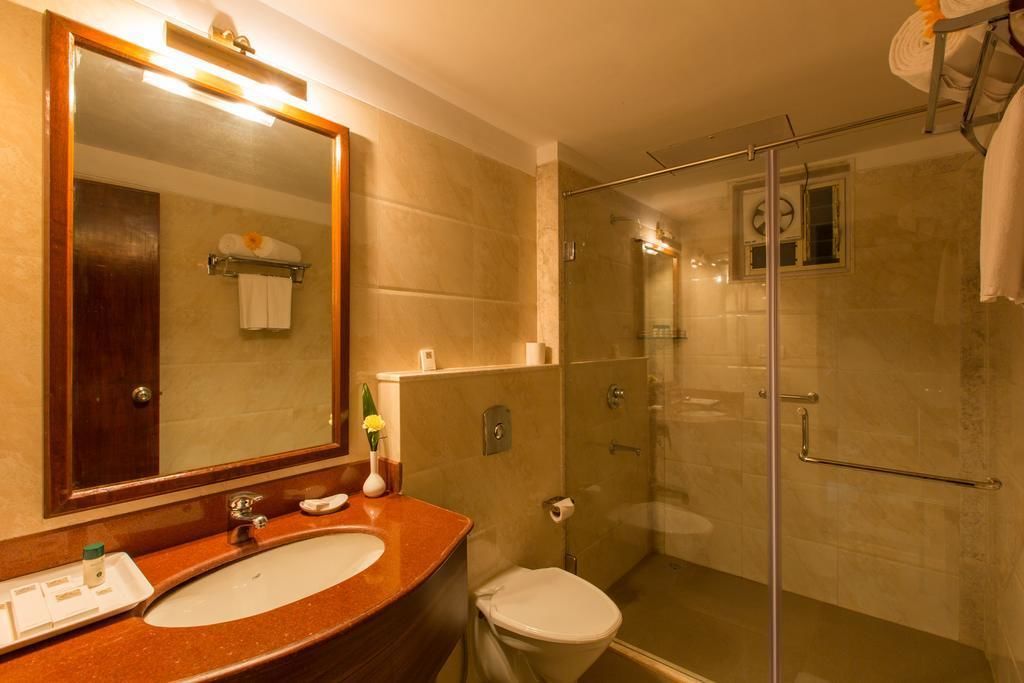 A bathroom with a large mirror, a sink, a toilet, and a glass-enclosed shower area.