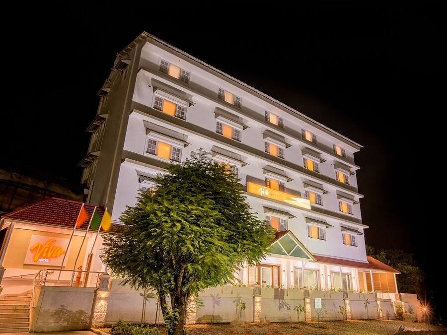 A multi-story hotel with a well-lit facade and a tree in front.