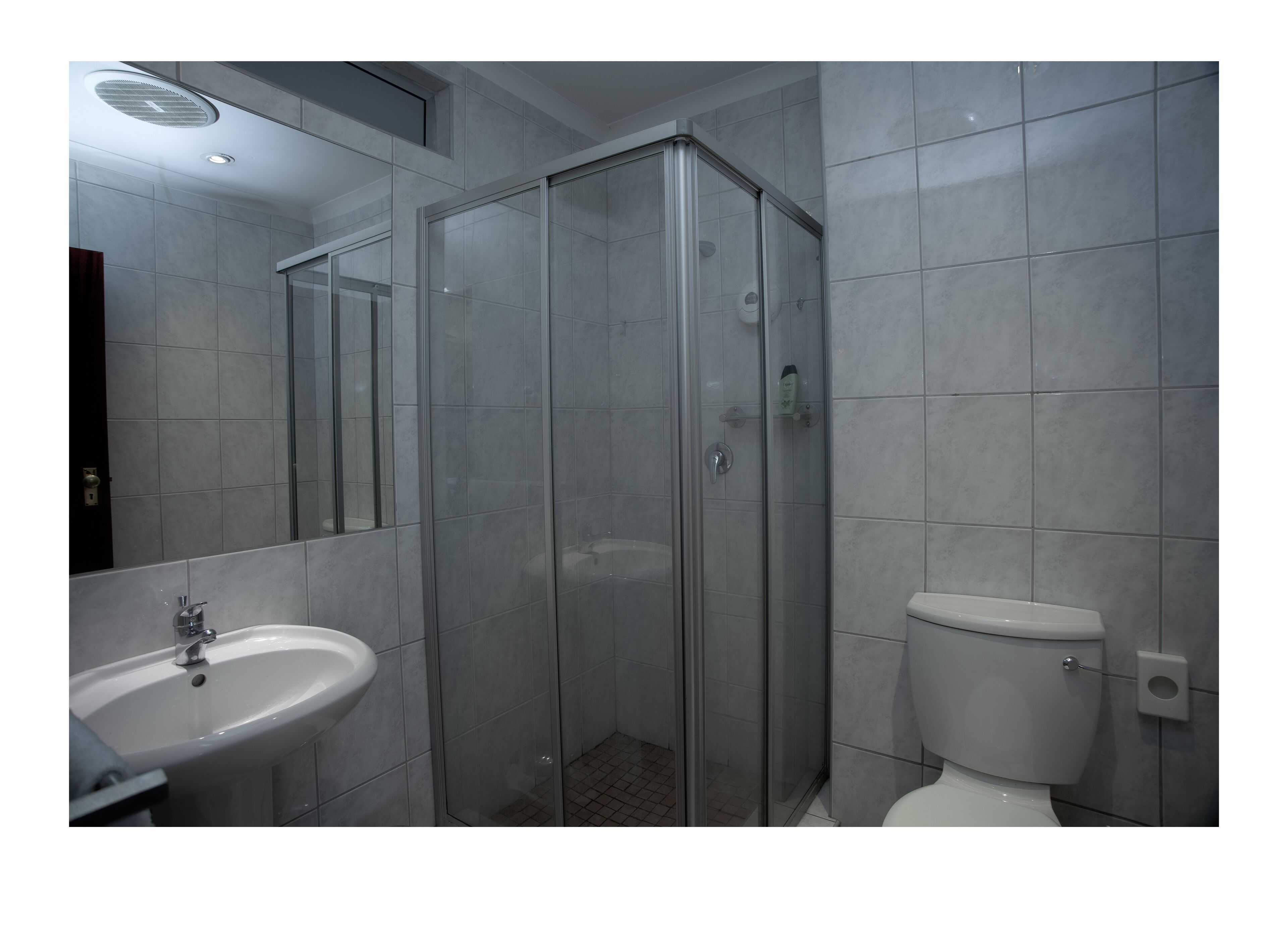 A modern bathroom with a glass-enclosed shower, a white sink, and a toilet.