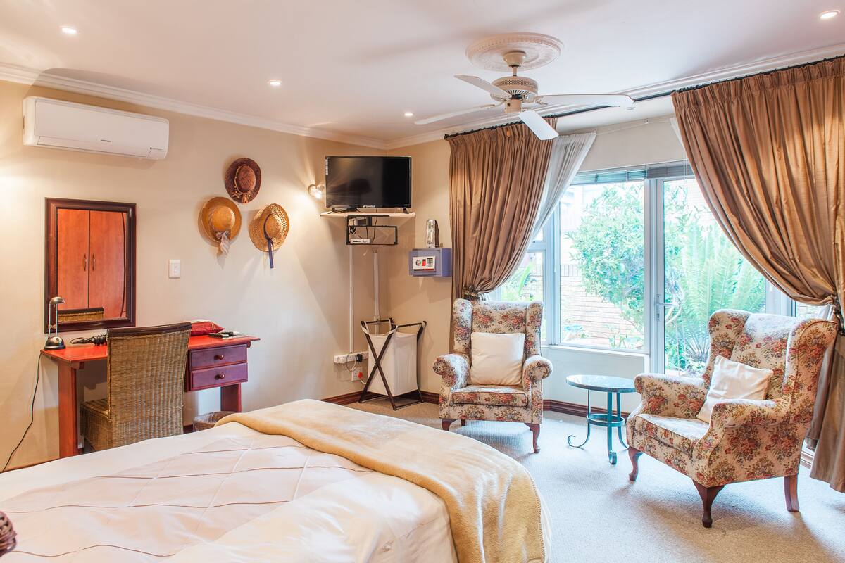 Habitación de hotel con cama, escritorio, silla, televisión y ventilador de techo.