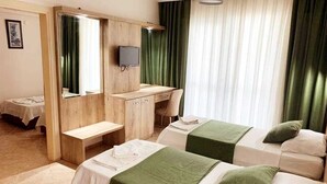 A hotel room with two beds, a desk, a mirror, and a television. - Melodi Club Hotel (Kusadasi)