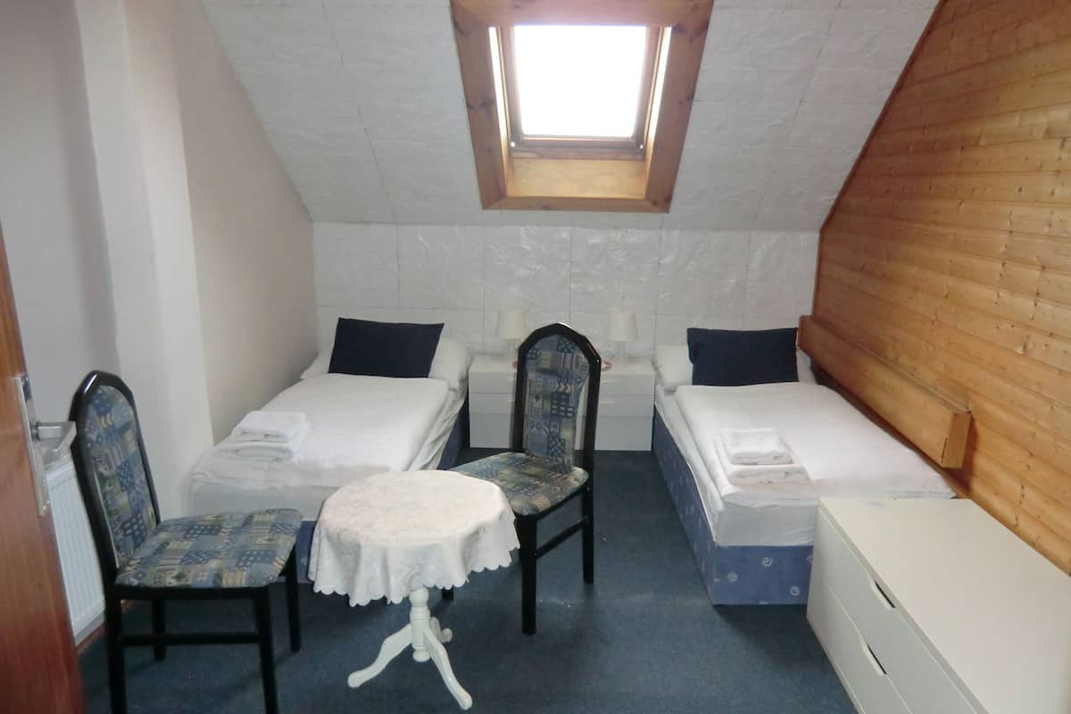 A small, cozy room with two single beds, a small table, and two chairs.