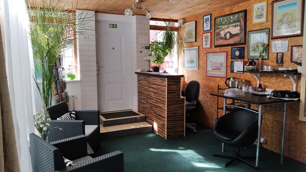 A cozy reception area with wicker furniture, a wooden reception desk, and a wall adorned with framed artwork. - Orbis (Prague)