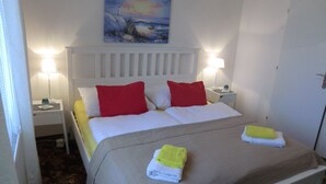 A neatly made bed with a white headboard, red and white pillows, and two folded towels on the bed. - Orbis (Prague)