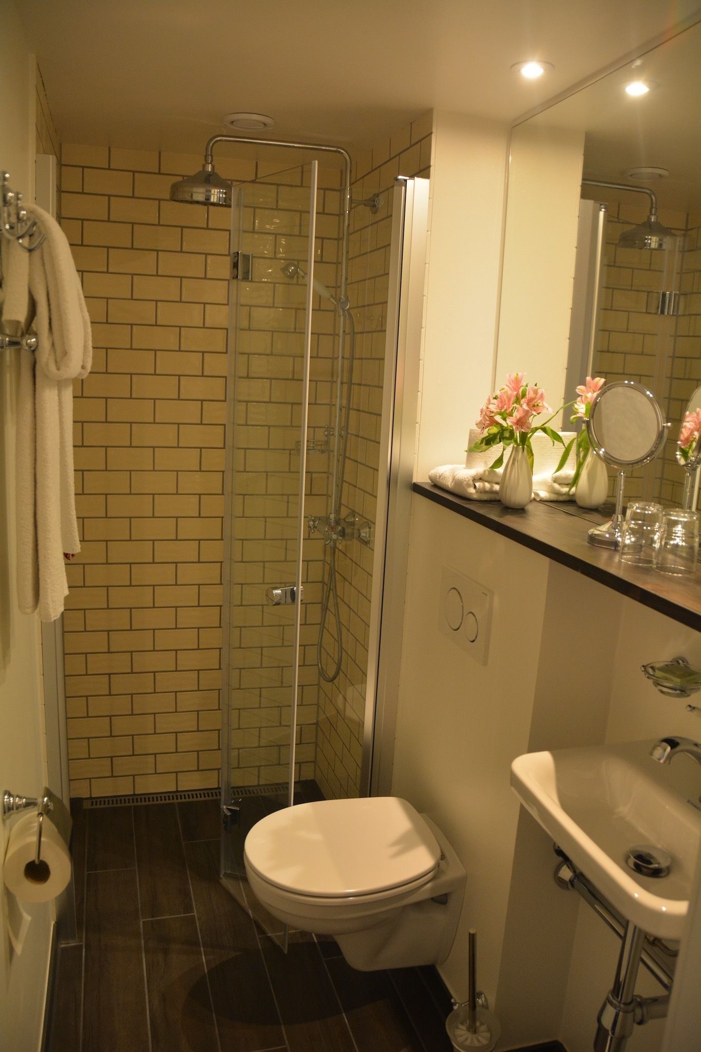 A bathroom with a shower, toilet, sink, and mirror.