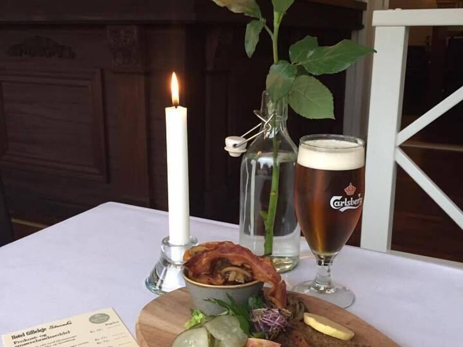 A wooden board with food, a candle, a glass of beer, and a menu.
