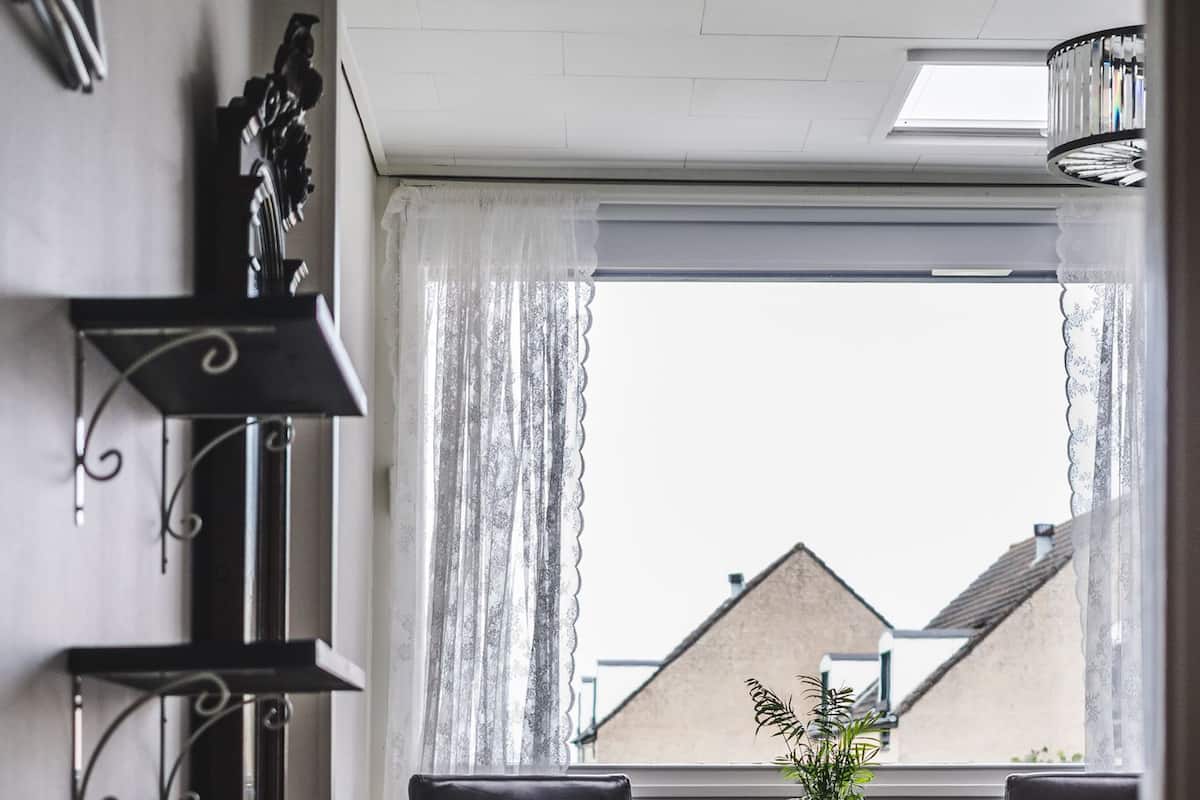 Ein Wohnzimmer mit einer Couch, zwei Sesseln, einem kleinen Tisch und einem Blumentopf an einem fensterbepflanzten Fenster.