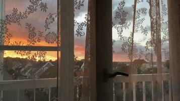 A door with a view of a sunset through lace curtains.