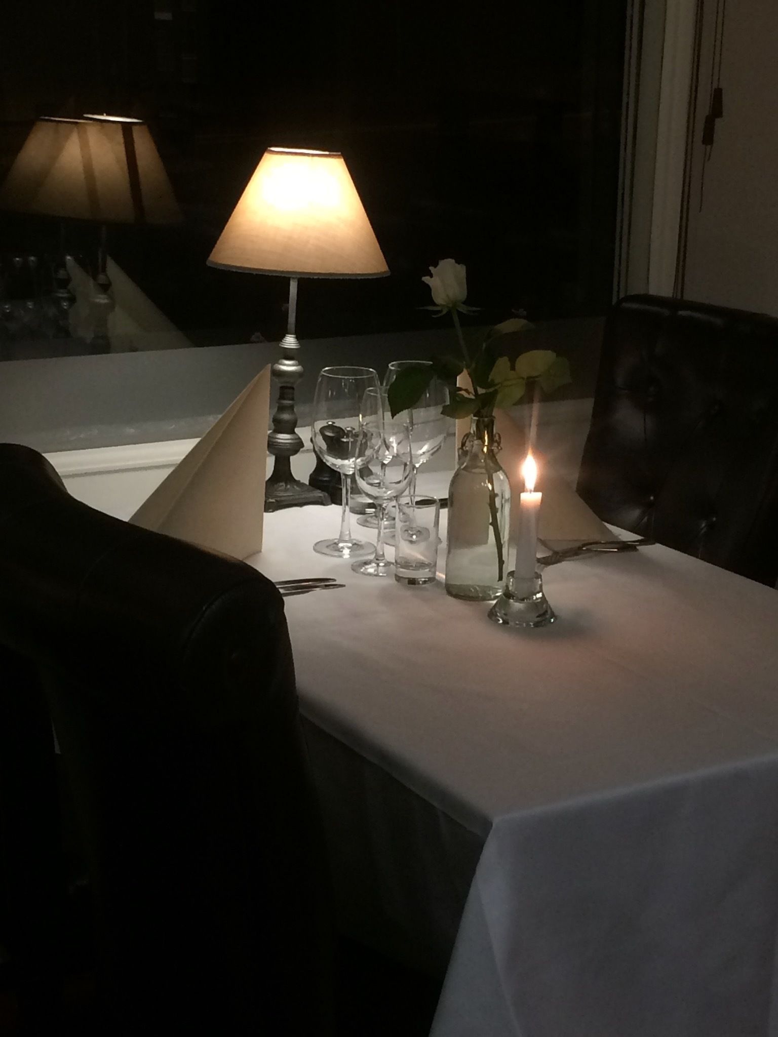 A table set for dining with glasses, a candle, and a vase with flowers.
