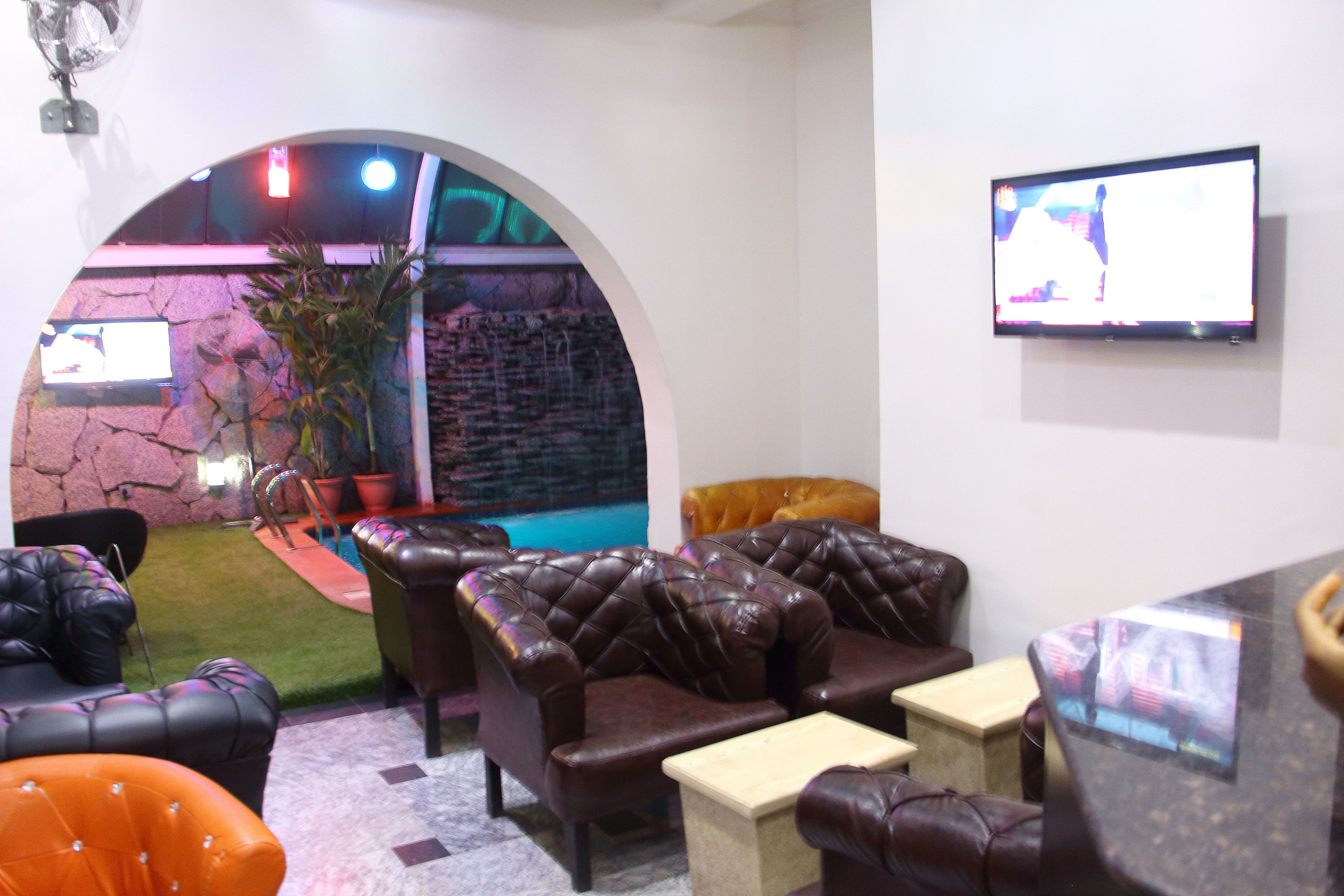 A lounge area with leather sofas, a small table, and a TV screen.