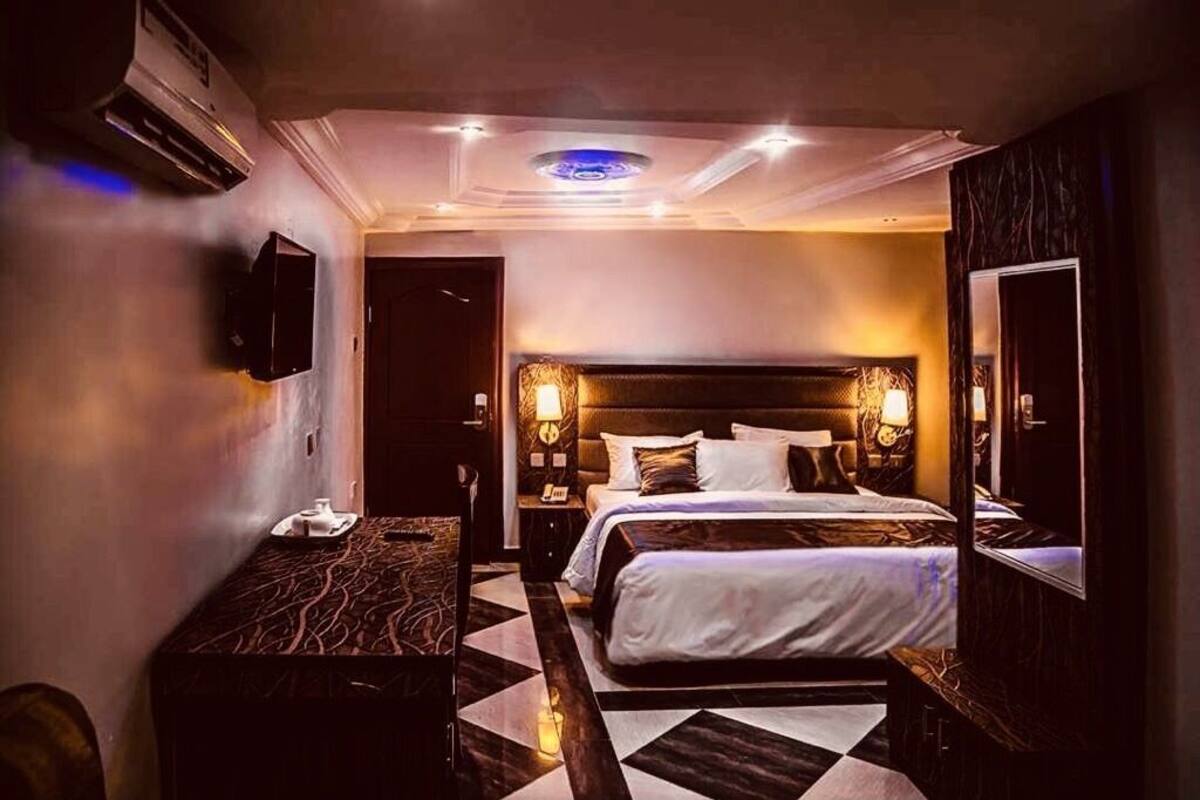 A hotel room with a large bed, a desk, and a TV mounted on the wall.