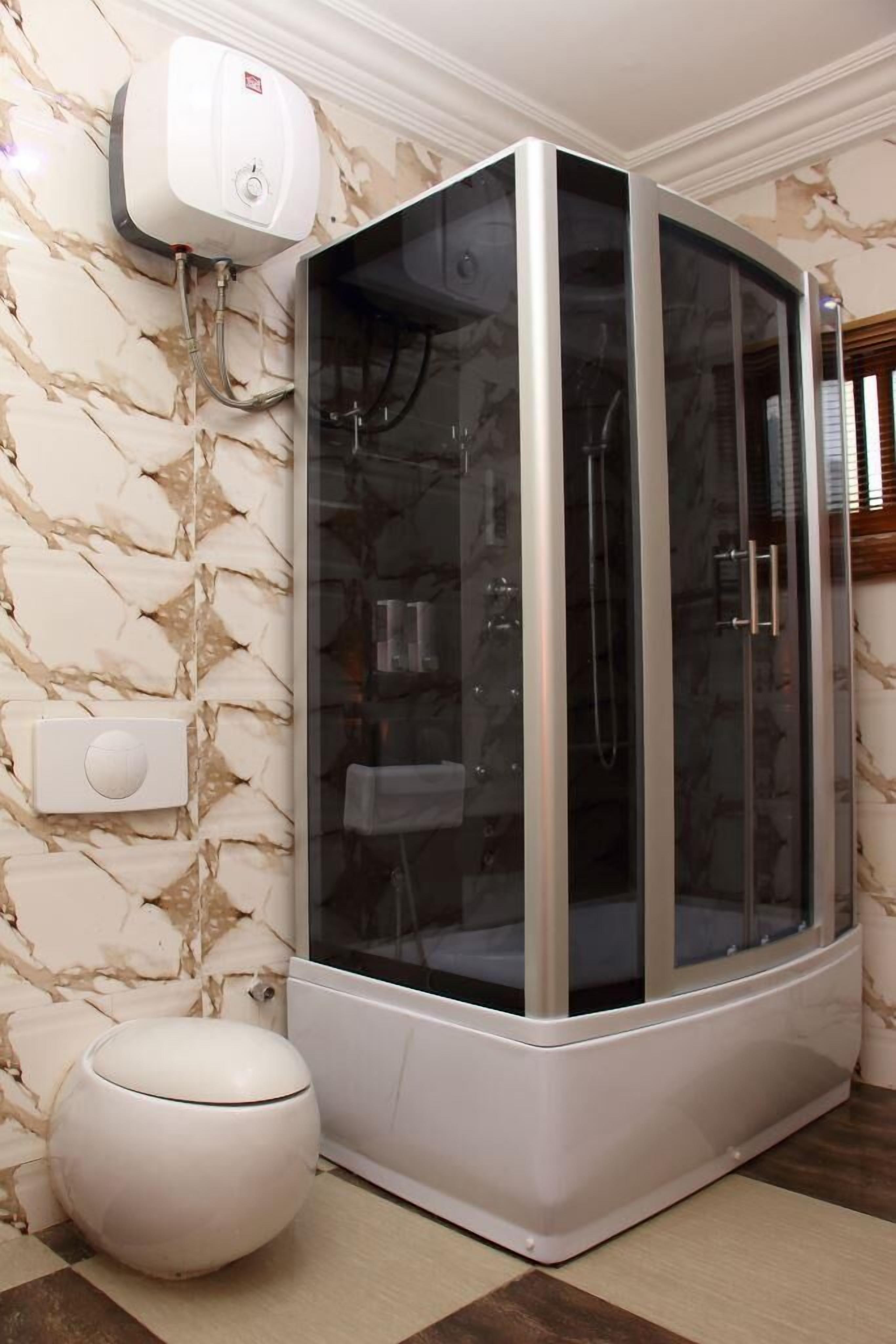 Un baño moderno con ducha de vidrio, inodoro y pared con diseño de mármol.