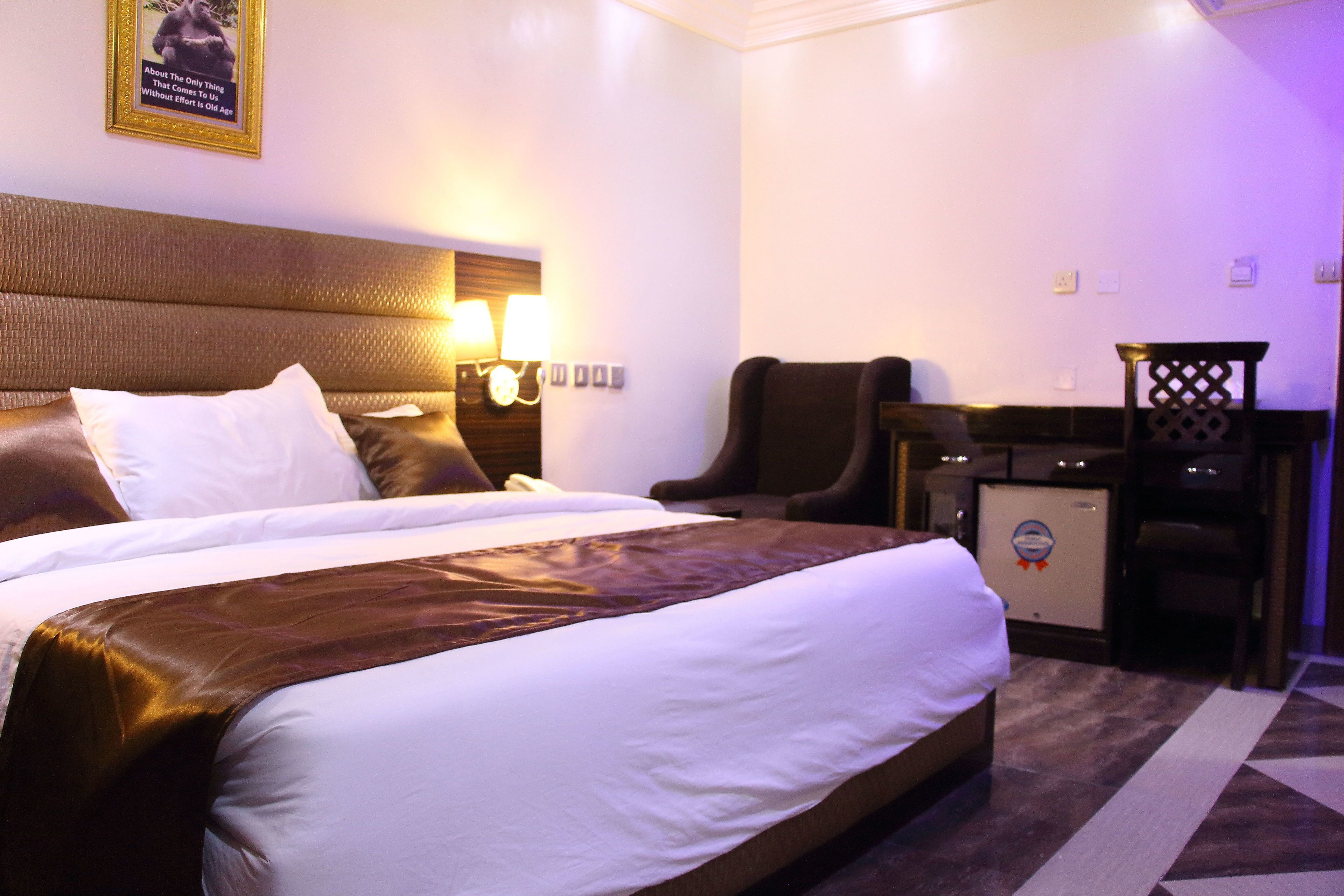 Una habitación de hotel con una cama grande, un escritorio, una silla y un refrigerador pequeño.