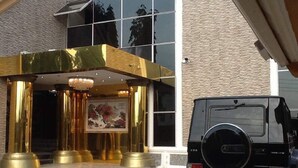 Entrada de un edificio con un vehículo negro estacionado frente a él.