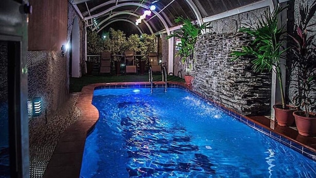 Una piscina interior con pared de piedra y plantas en macetas.