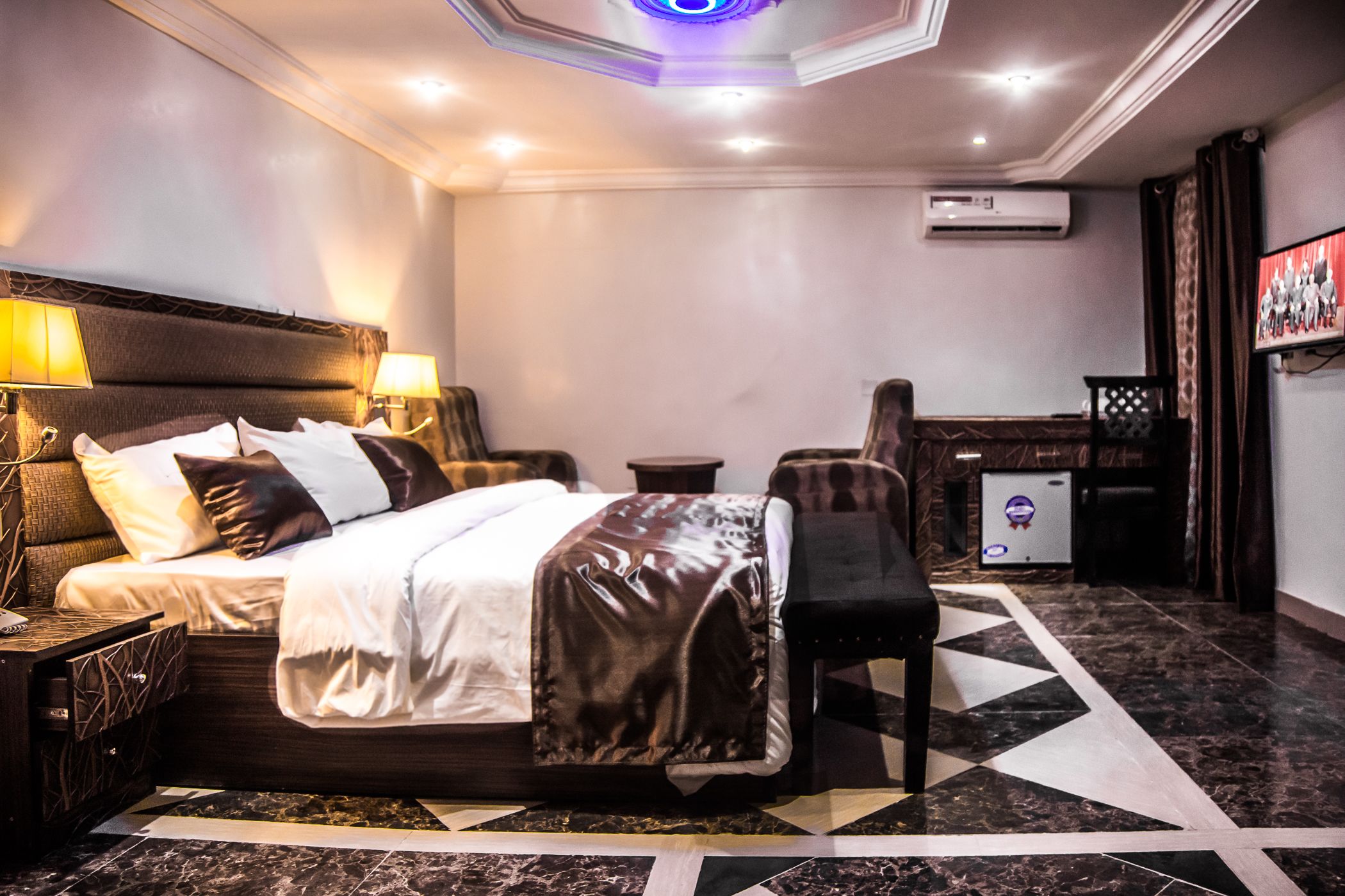 A hotel room with a large bed, bedside lamps, a TV, and a desk with a chair.