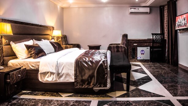 Ein Hotelzimmer mit einem großen Bett, Nachttischlampen, einem Fernseher und einem Schreibtisch mit Stuhl.