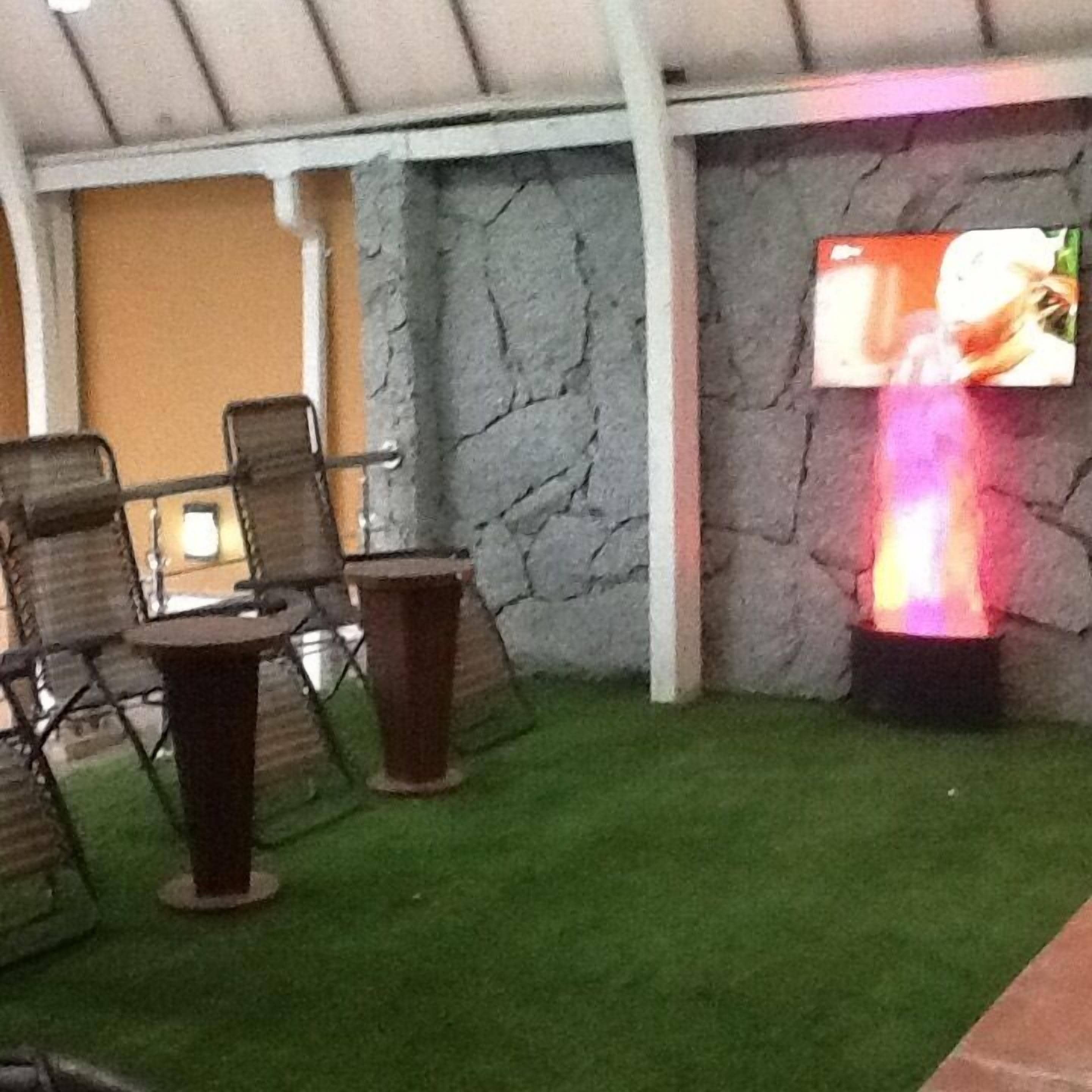 An outdoor seating area with stone walls and a flat-screen TV mounted on the wall.