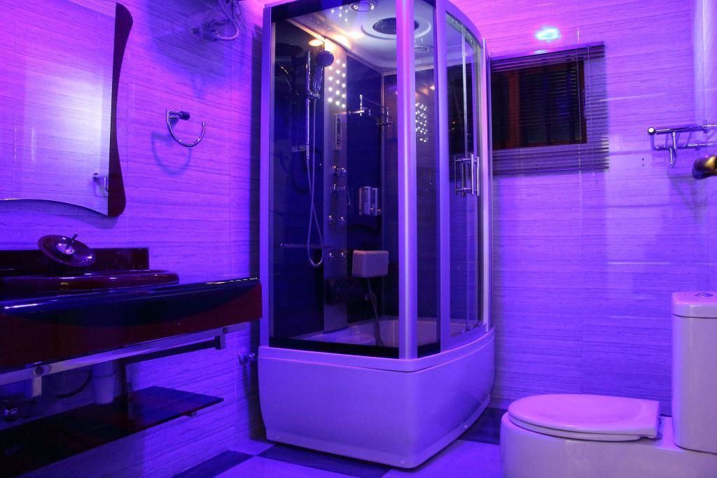 A modern bathroom with a glass-enclosed shower, a white toilet, and a sink with a mirror.