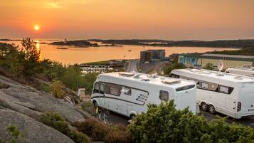 Een camping met campers langs het water tijdens zonsondergang.
