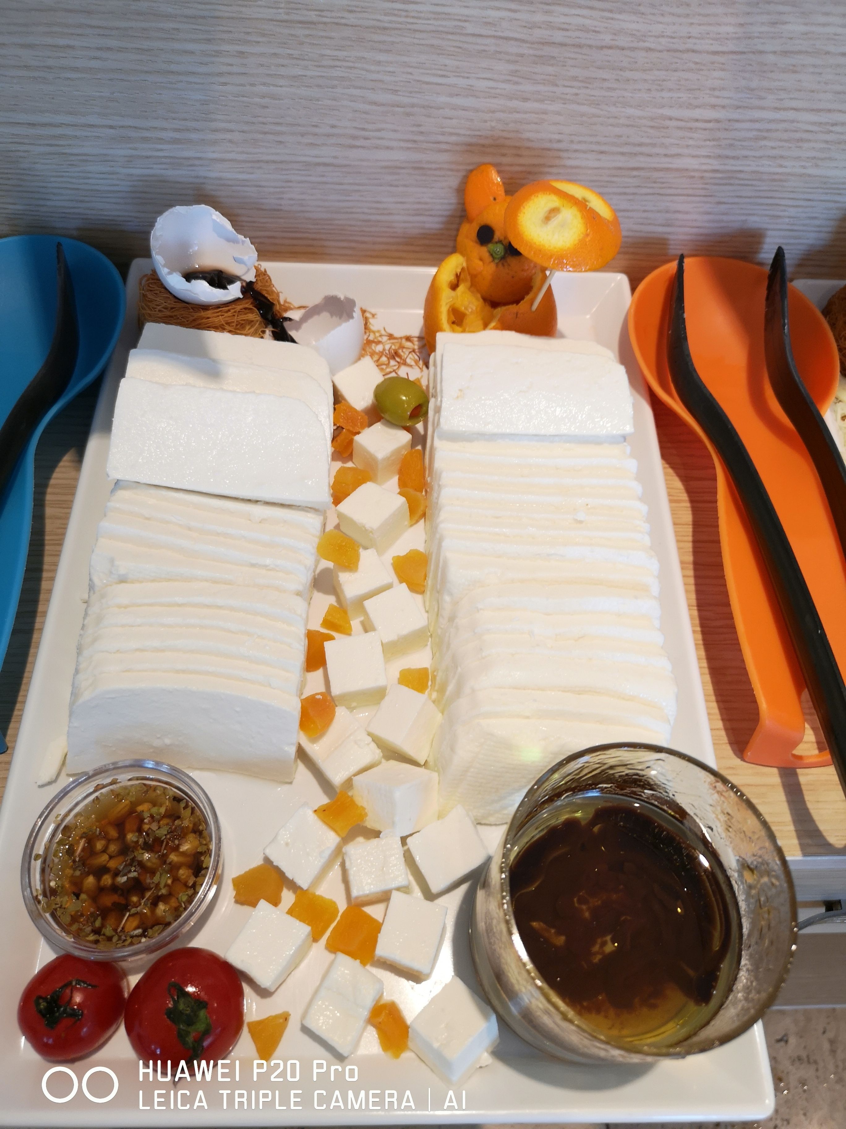 A white rectangular plate with white rectangular blocks, orange cubes, and a small bowl of sauce.