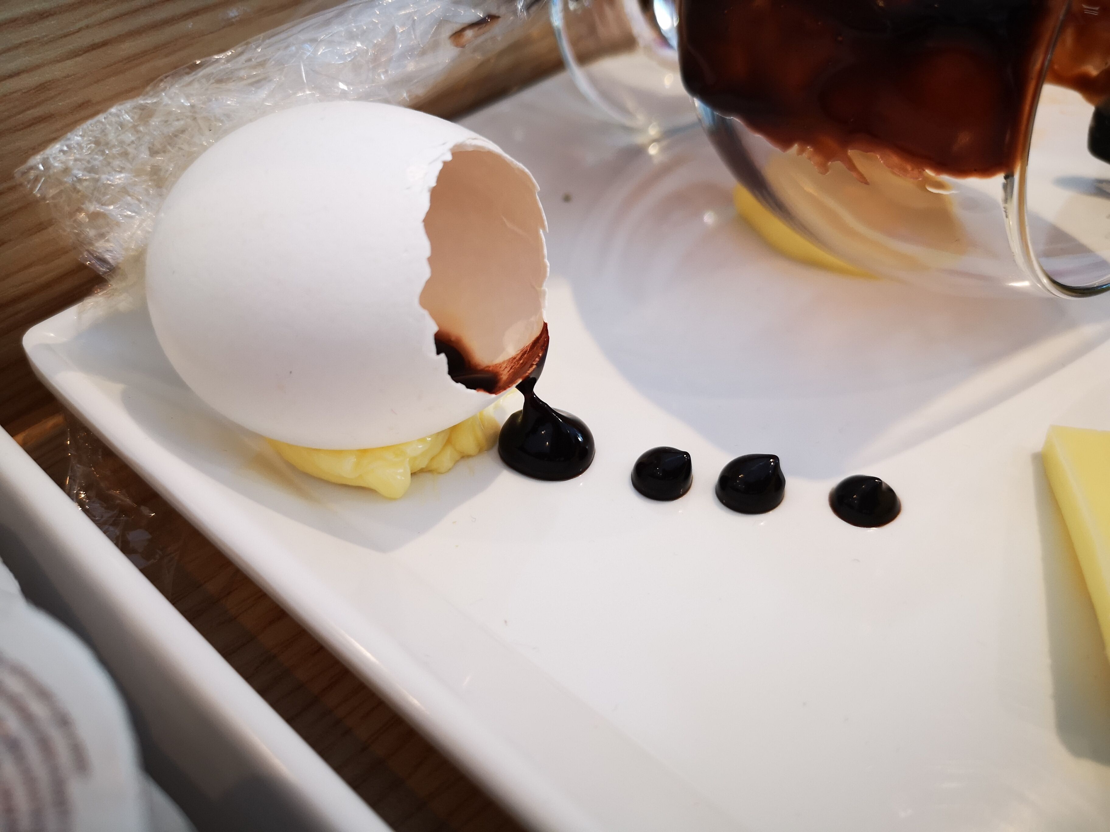 A dessert with a cracked egg shell on a white plate.