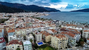 A coastal cityscape with dense residential buildings, a marina with numerous boats, and a clear view of the sea and mountains in the background. - City Hotel Marmaris (Marmaris)