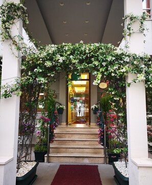 A hotel entrance with a red carpet leading to a staircase, surrounded by lush greenery and white flowers. - City Hotel Marmaris (Marmaris)