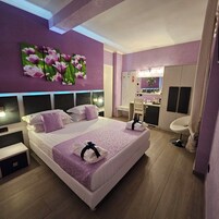 Una habitación de hotel moderna con una cama grande, un tocador con espejo y una zona de estar.