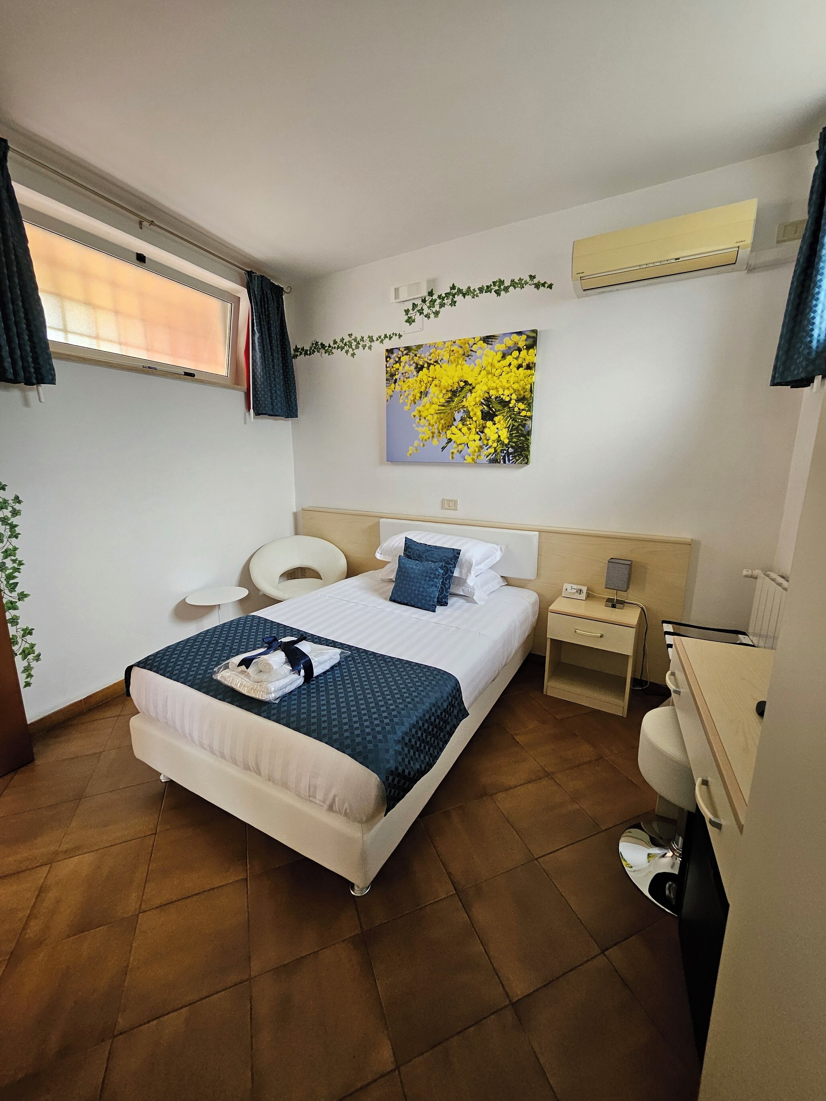 Un dormitorio ordenado con cama, mesitas de noche, un escritorio y un inodoro.