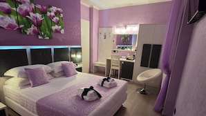 Een moderne slaapkamer met een groot bed, een kaptafel met spiegel, en een zithoek.