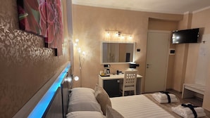 Een hotelkamer met een bed, nachtkastje, lamp, spiegel en televisie.