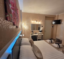 Habitación de hotel con cama, mesita de noche, lámpara, espejo y televisor.