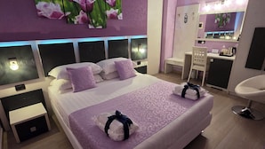 Een moderne slaapkamer met een groot bed, nachtkastjes, een bureau en een spiegel.
