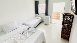 Una habitación de hotel con dos camas, una mesita, un televisor y una ventana con cortinas.