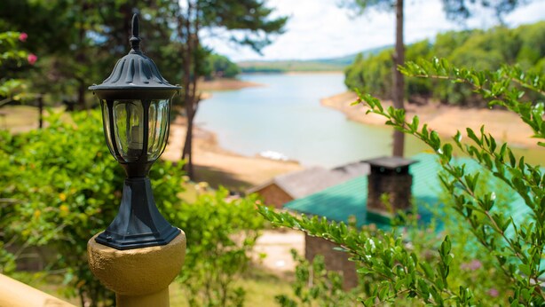 A lamp post on a balcony overlooking a river and greenery. - Le Chateau du Lac (Mantasoa)