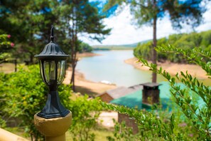 A lamp post on a balcony overlooking a river and greenery. - Le Chateau du Lac (Mantasoa)