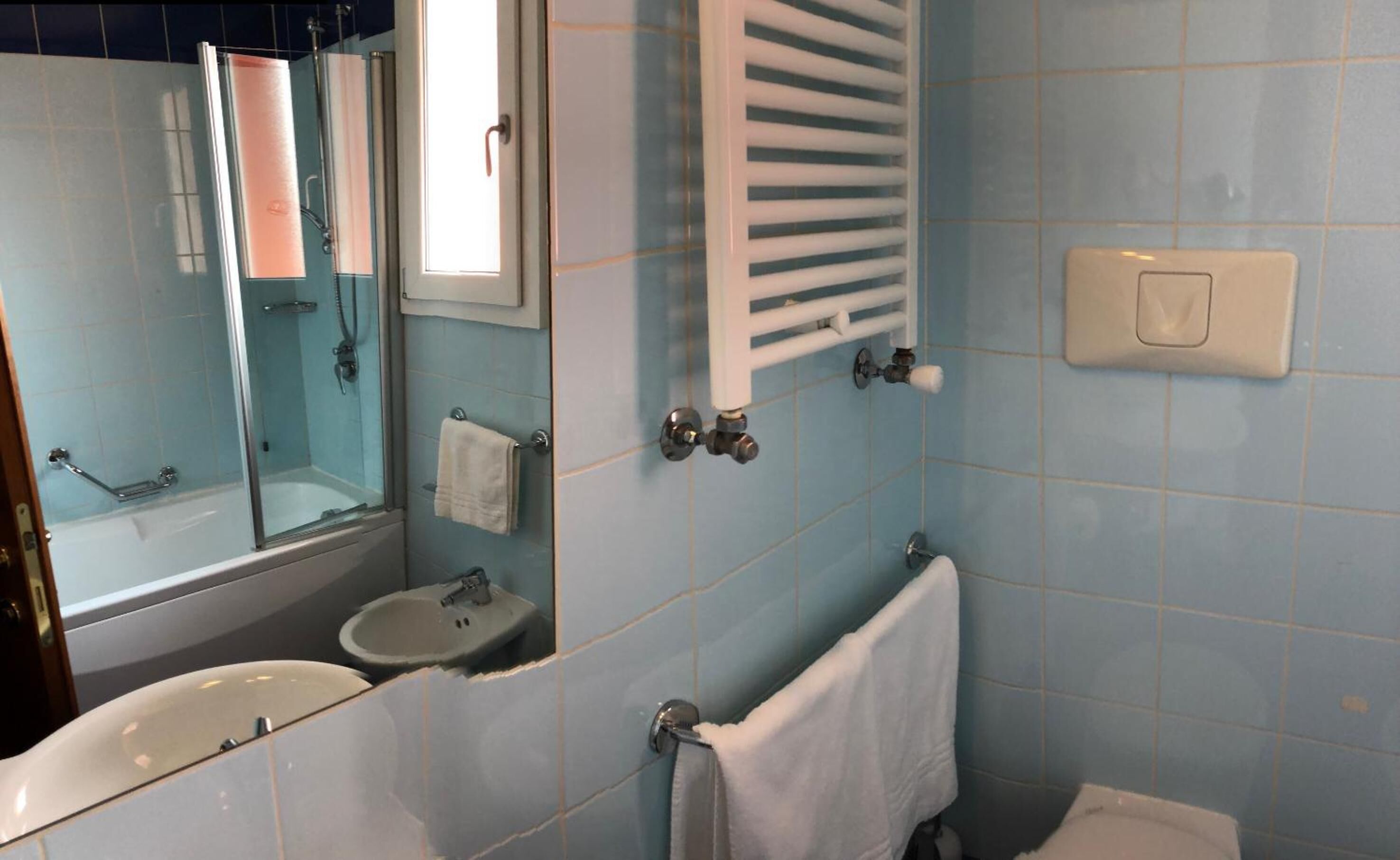 A bathroom with a sink, mirror, and shower.