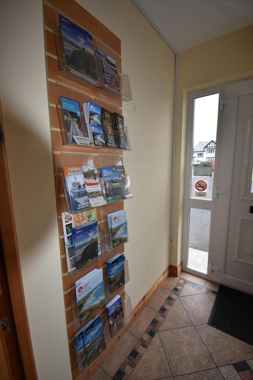 A hallway with a wall-mounted display of travel brochures and a door with a no-smoking sign.