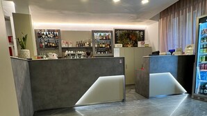 Een moderne receptie met een marmeren vloer, een bar met verschillende flessen en een beveiligingscamera aan het plafond.