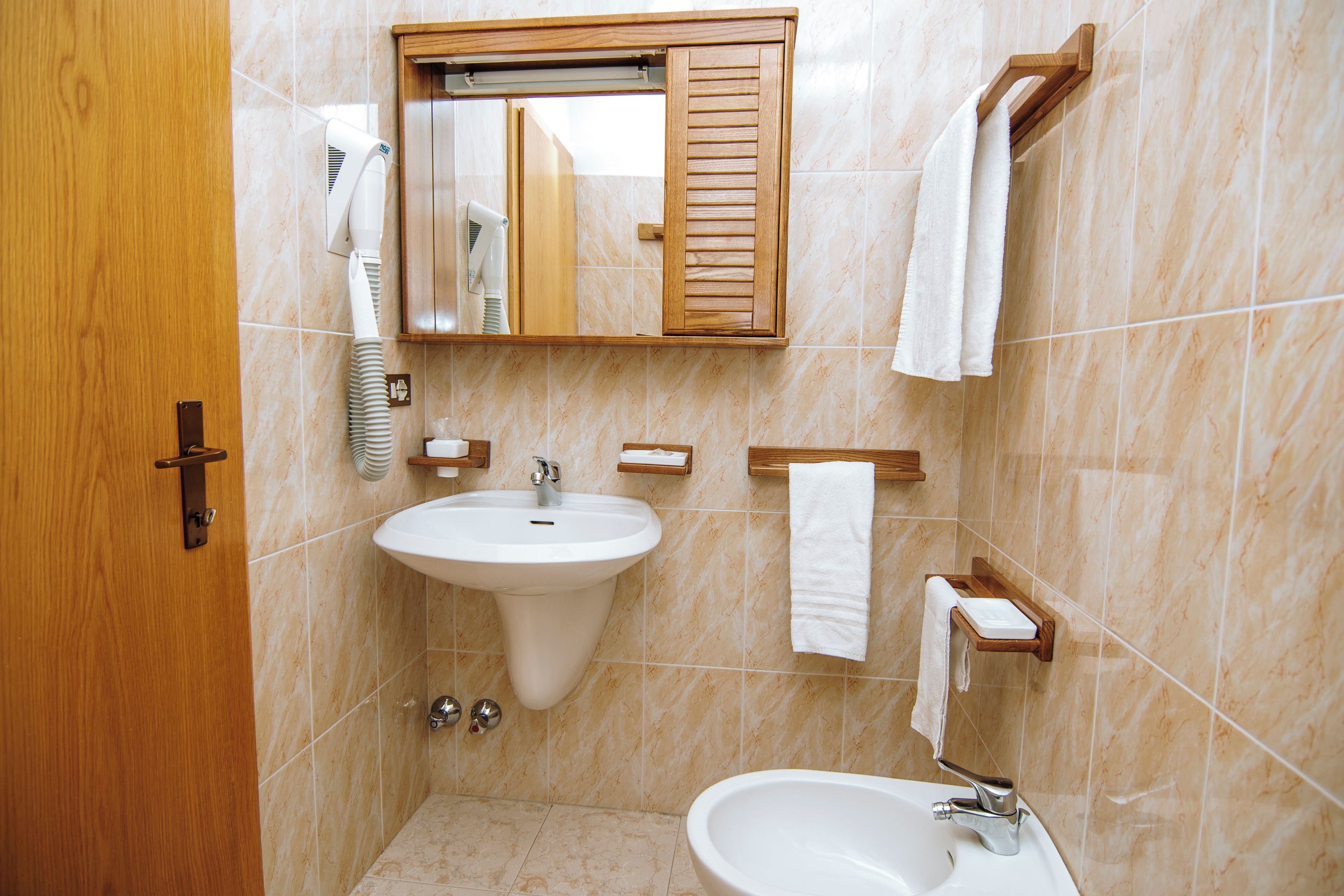 A bathroom with a sink, mirror, towel rack, and a door.