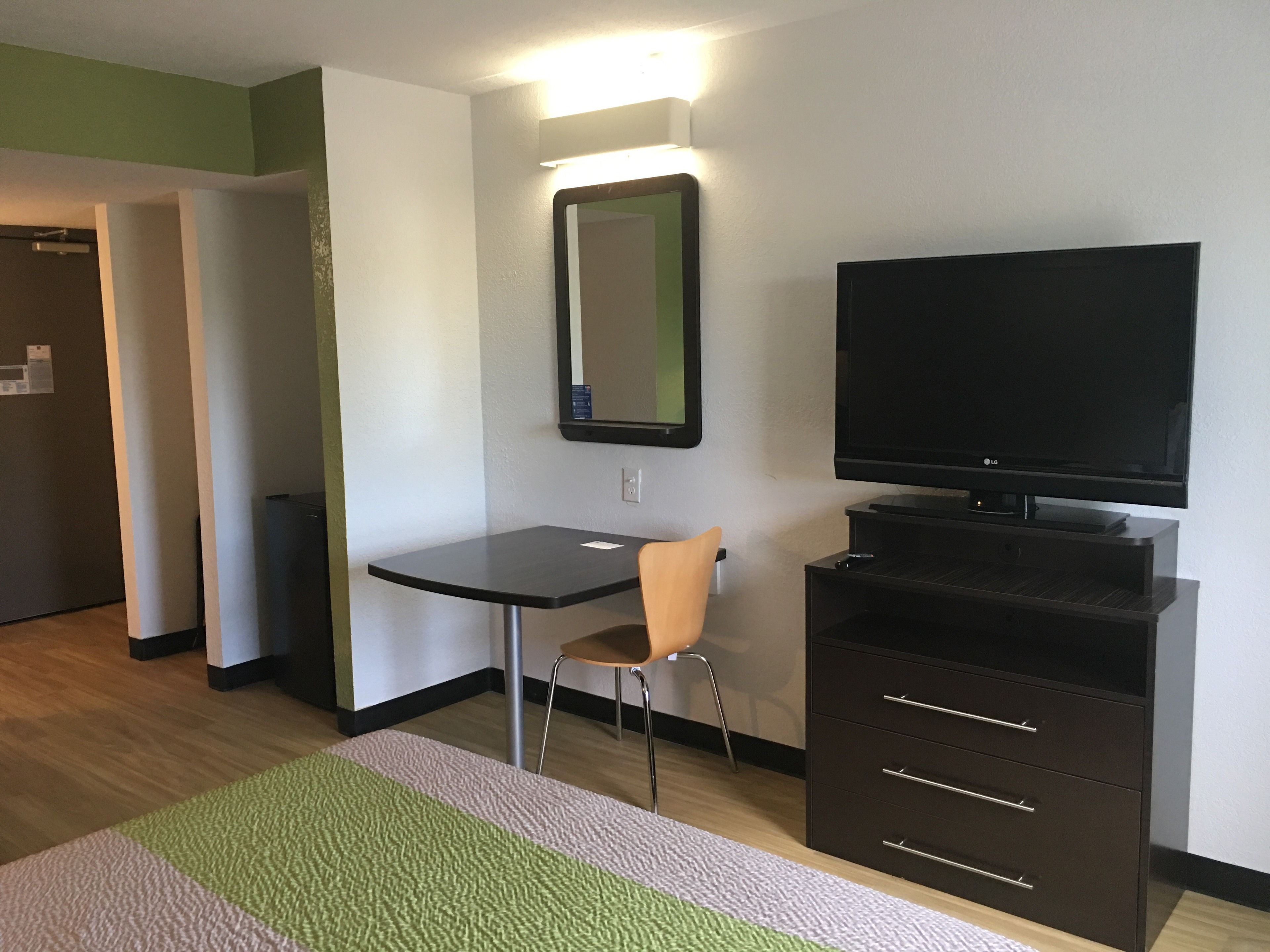 Un salon moderne avec un téléviseur à écran plat, une petite table, un fauteuil et un meuble.